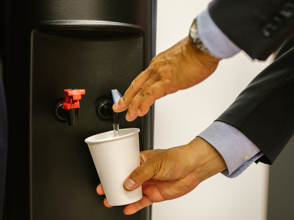 Persona sirviendo agua en vaso con dispensador de agua