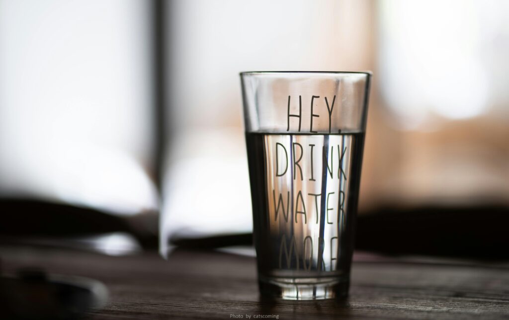 Vaso de agua en el que pone: "Hey, bebe agua más"